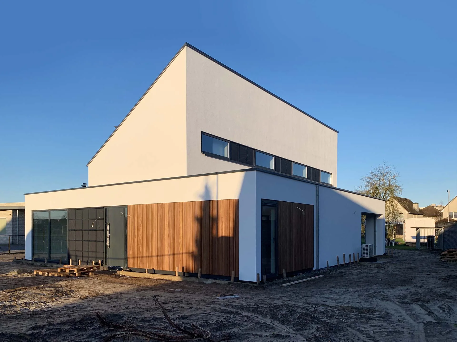 Residential building with white rendered walls, timber cladding and large glazed openings.