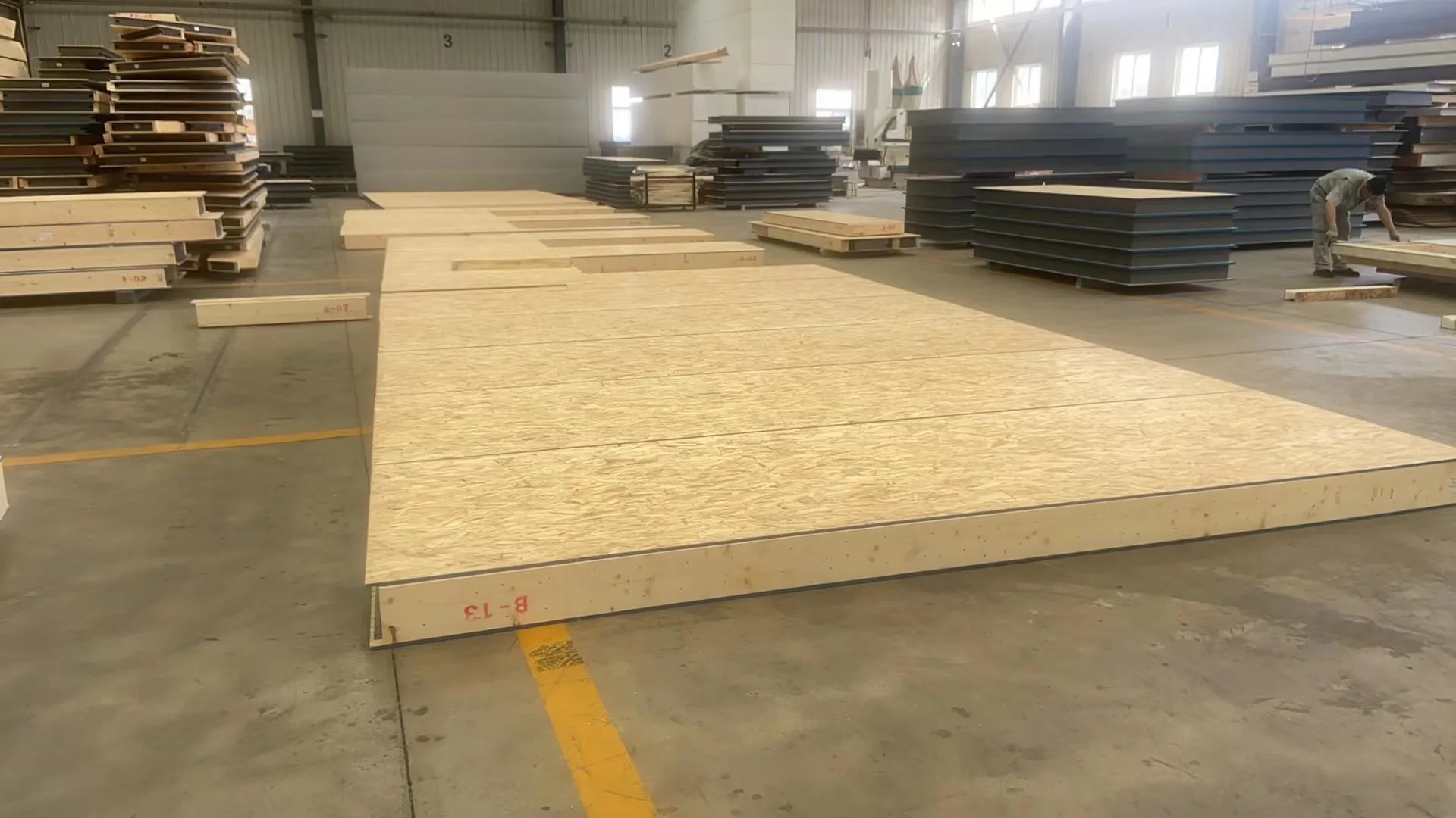 Prepared SIP elements laid out on the production floor with stacked panels in the background.
