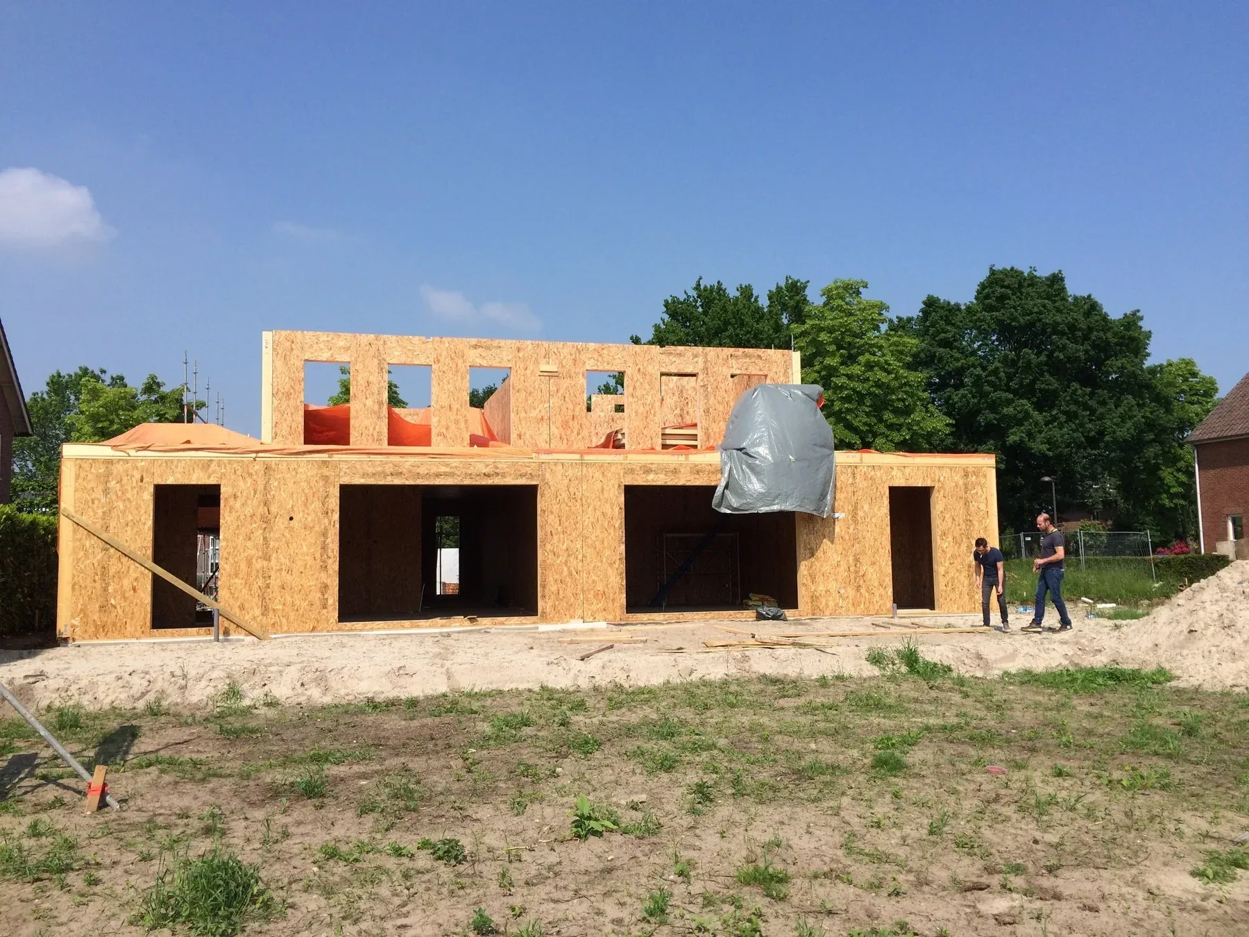 SIP building shell with OSB-faced wall panels and window and door openings during assembly.