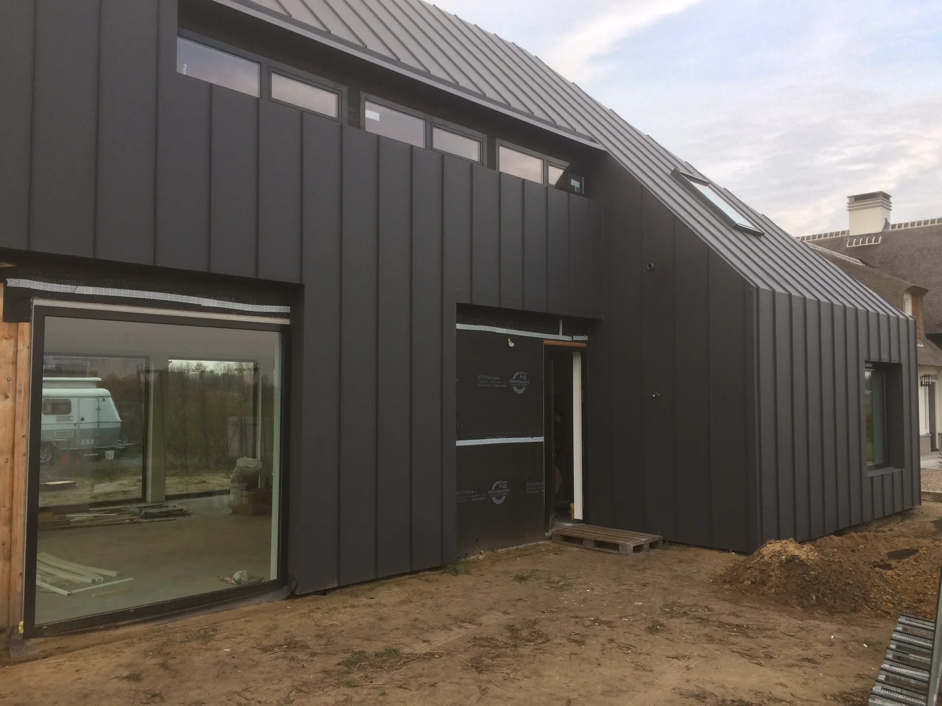 Dark-clad building exterior with large openings during finishing works