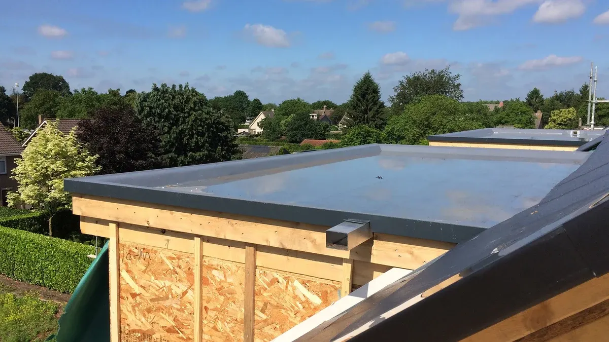 Roof membrane, edge trim, outlet and timber battens above an OSB-faced wall.