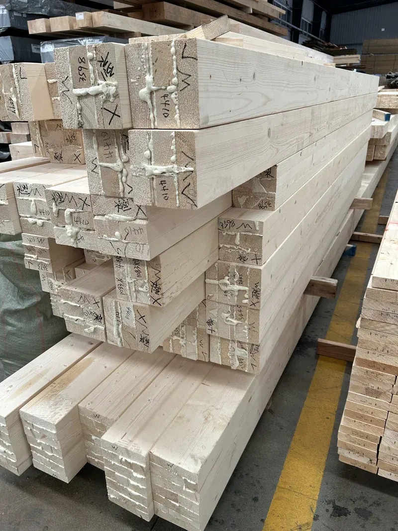 Stacked timber components with machined notches in a factory.