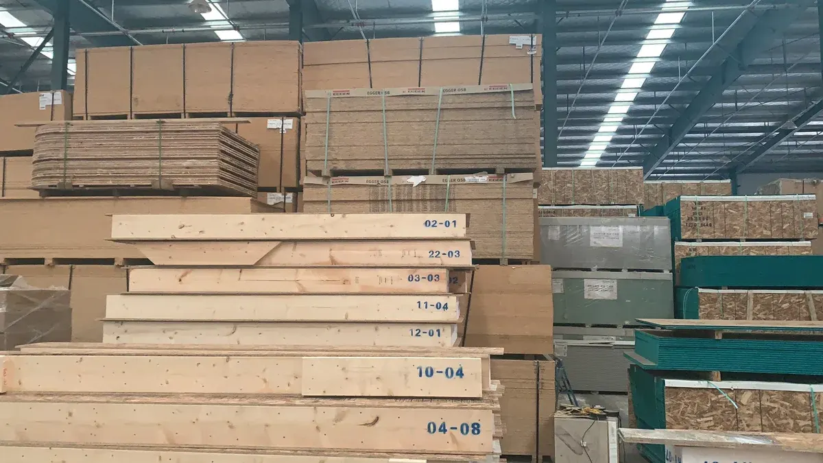 Numbered panel stacks and timber components arranged in a factory.