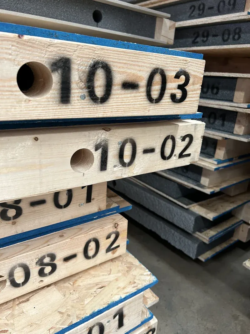 Identification numbers marked on timber edges beside grey insulation and OSB panel faces.