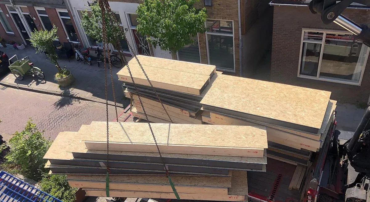 Stacked SIP wall panels being lifted from a delivery vehicle with crane slings.