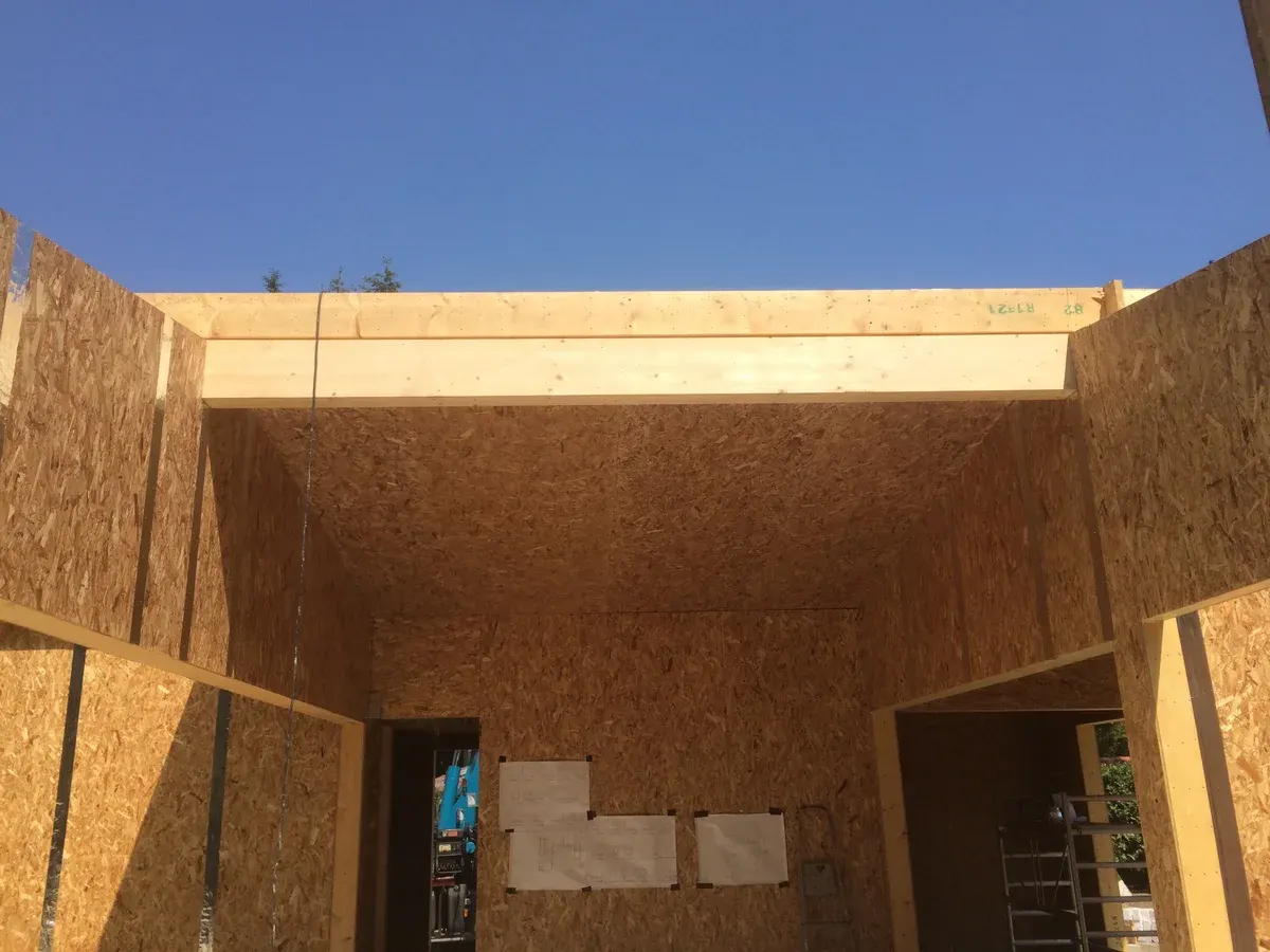 Timber beam above a wide opening between OSB-faced walls.