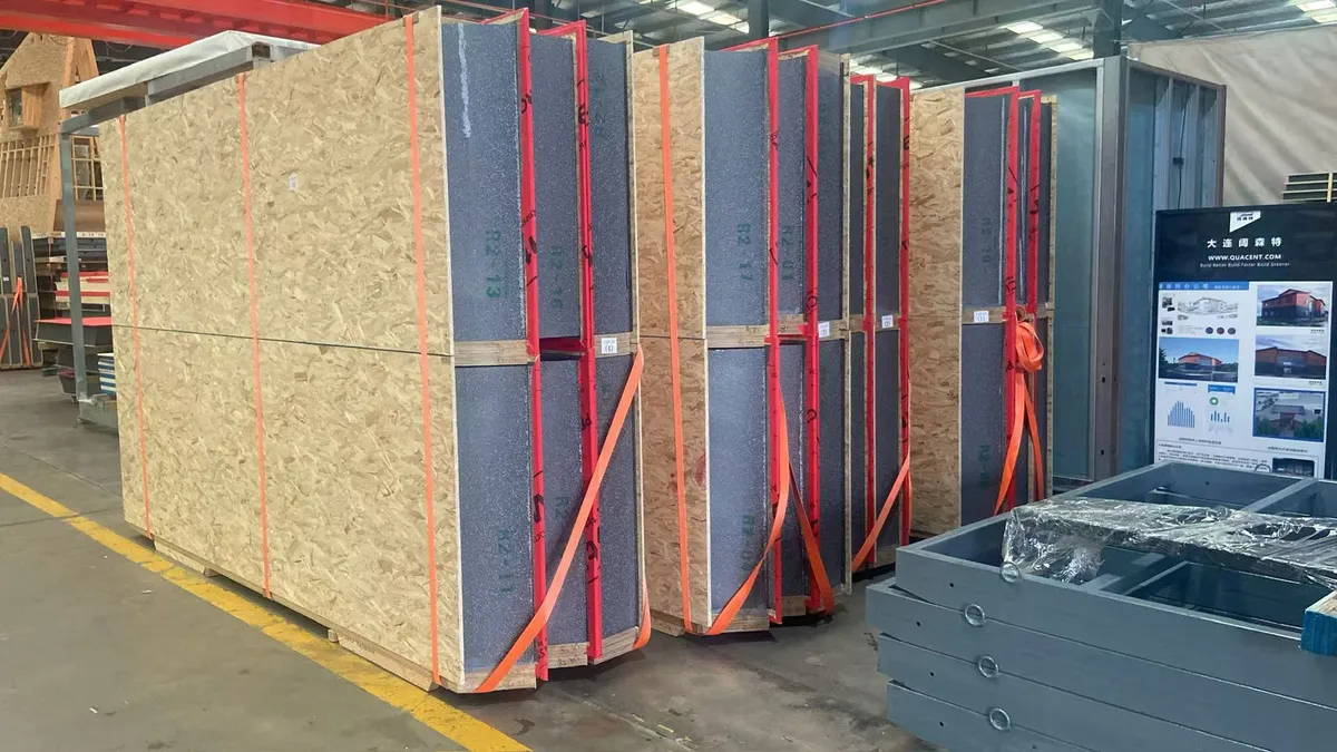 Upright SIP elements secured in red transport frames inside the production facility.